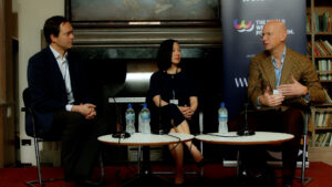 Prof Jan Emmanuel De Neve, Dr Diana Han and Alberto Nobis on the stage at the World Wellbeing Policy Forum 2024