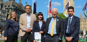 Sarah Cunningham, Prof Jan-Emmanuel De Neve, Dr Maria Cotofan, Prof Lord Richard Layard, and Ben Wealthy pose with the 2025 UK Wellbeing Report in front of the Palace of Westminster.